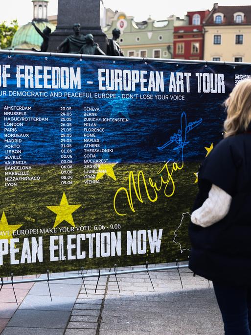 Polnische Passantin vor einem Plakat zu einer Kunstausstellung mit dem Titel: "Labyrinth Of Freedom - European Art Tour", die die Menschen zur Teilnahme an der EU-Wahl anregen will. 