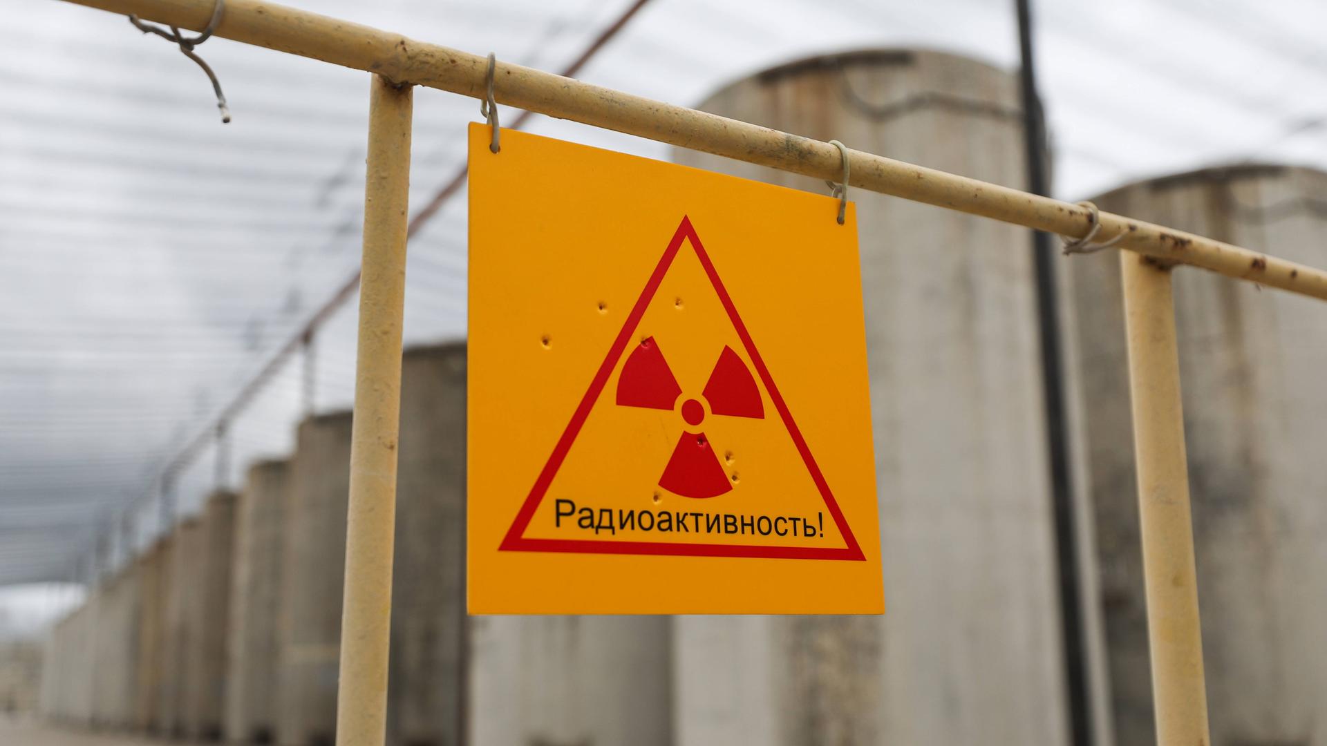 Ein gelbes Atomkraft-Warnschild mit roter Schrift vor dem Gelände des ukrainischen Atomkraftwerks Saporischschja.