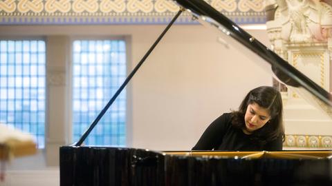 Eine Frau sitzt konzentriert am Klavier und spielt. 