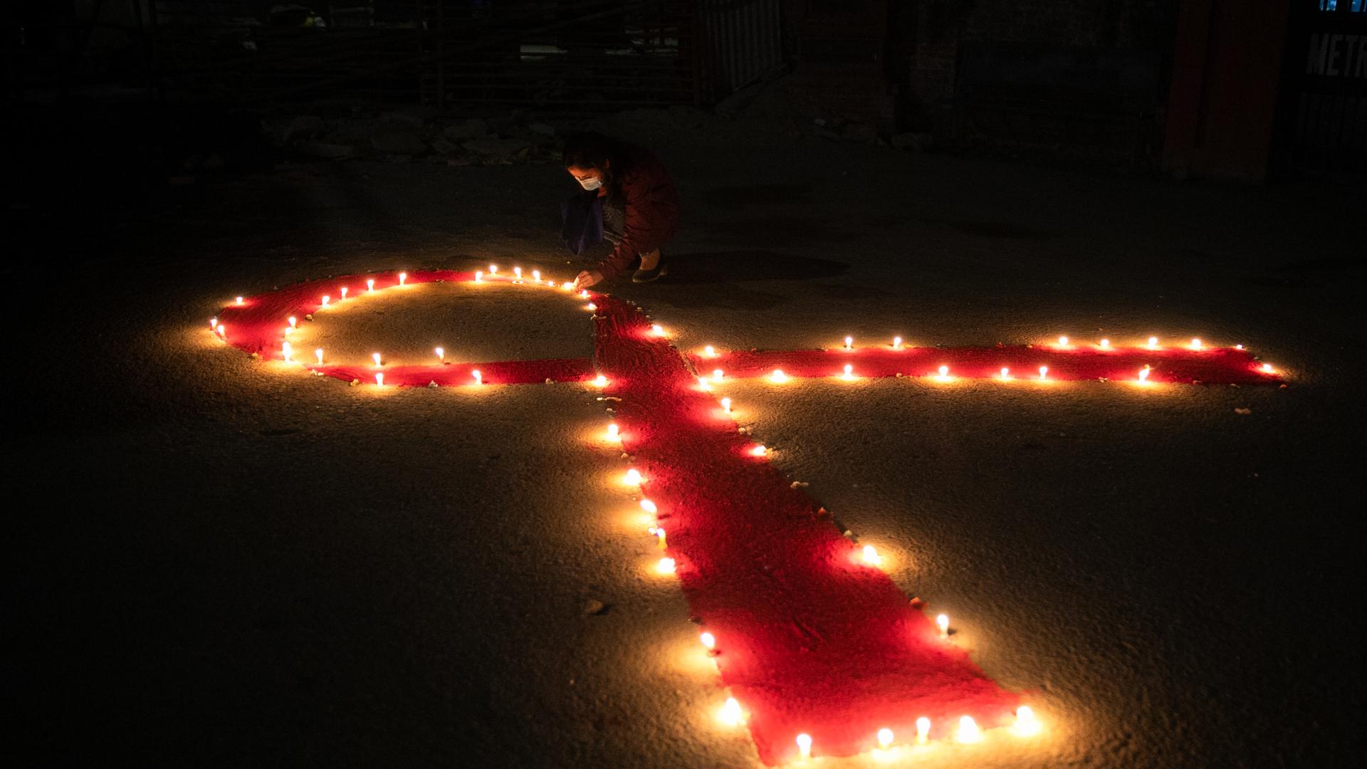 Viele Kerzen formen eine rote Schleife anlässlich des Welt-Aids-Tages