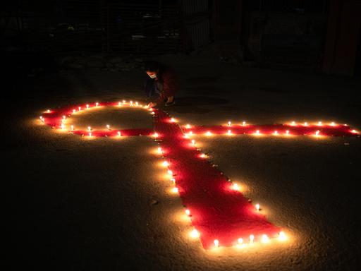 Viele Kerzen formen eine rote Schleife anlässlich des Welt-Aids-Tages