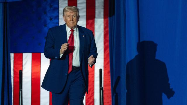 Donald Trump auf einer Bühne, im Hintergrund hängt eine USA-Flagge.