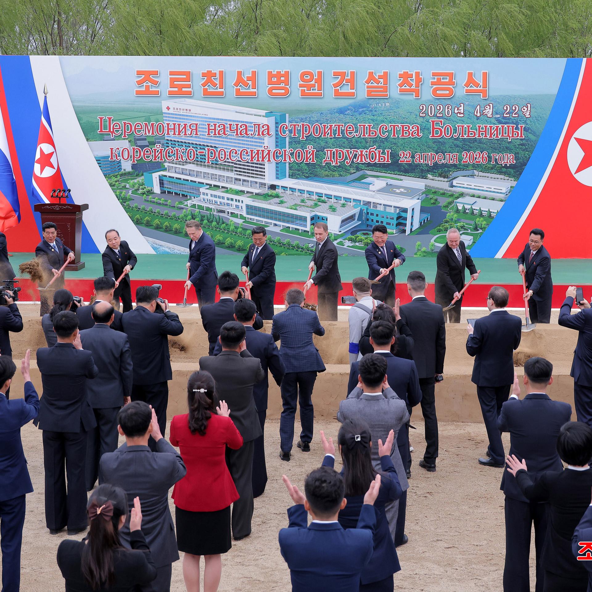 Der russische Gesundheitsminister Muraschko und weitere Vertreter nehmen an einer Feier zum ersten Spatenstich für ein nordkoreanisch-russisches Freundschaftskrankenhaus teil. Im Hintergrund ist ein Banner mit einem Bild der geplanten Klinik zu sehen.