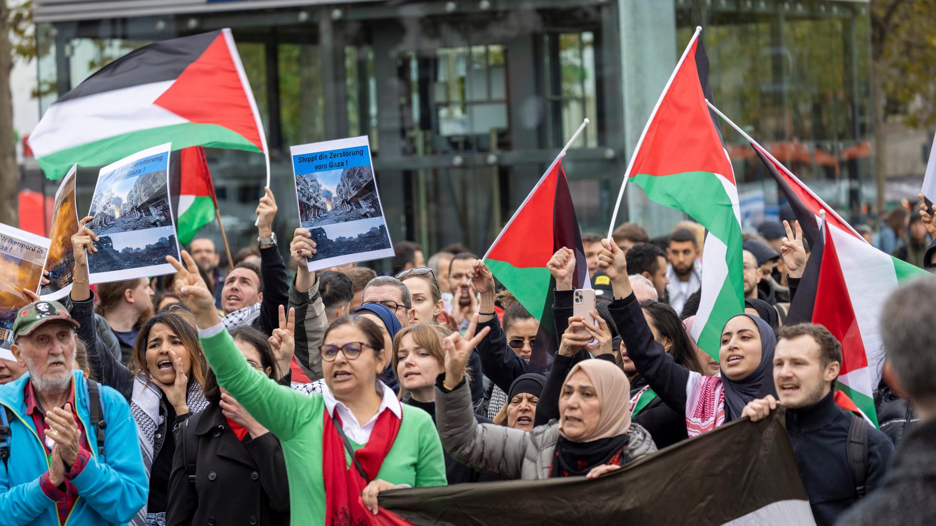 Teilnehmer einer Pro-Palästina-Kundgebung stehen mit Fahnen auf dem Heumarkt in Köln.