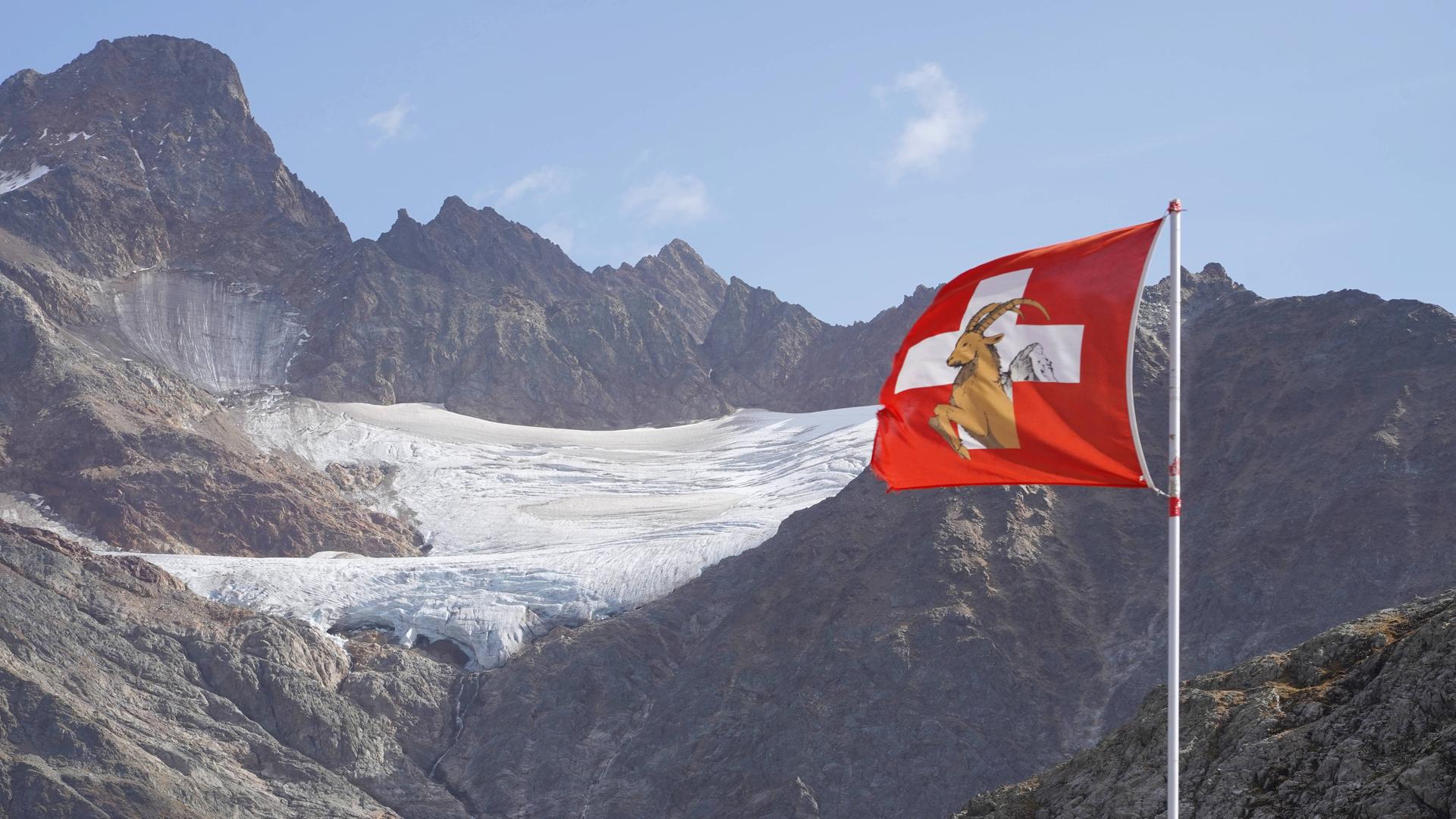 Eine Schweizer Flagge weht vor dem Gletscher im Haslital im Berner Oberland. Ein Großteil der Felsen ist nicht mehr von Eis bedeckt.
