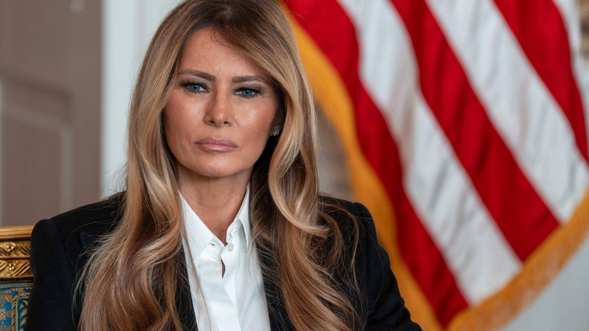 First Lady Melania Trump sitzt vor einer US-Flagge