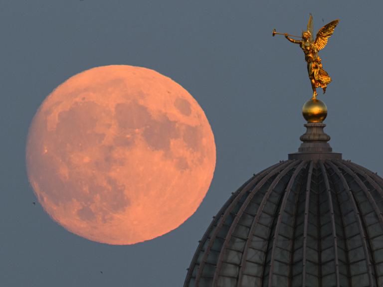 Der zunehmende Mond geht am Abend hinter der Kuppel der Dresdner Kunstakademie mit dem Engel "Fama" auf.