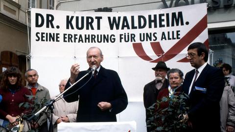 Kandidat Kurt Waldheim steht anlässlich der österreichischen Bundespräsidentenwahl 1986 vor einem Wahlplakat in eigener Sache und redet zum Publikum