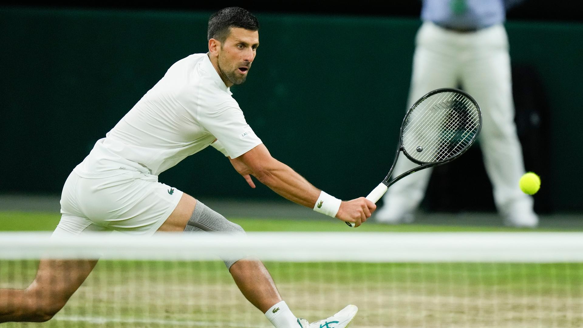 Novak Djokovic schlägt einen Ball auf dem Platz in Wimbledon.