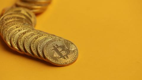 Fotoillustration zeigt die Kryptowährung Bitcoin auf gelbem Hintergrund.