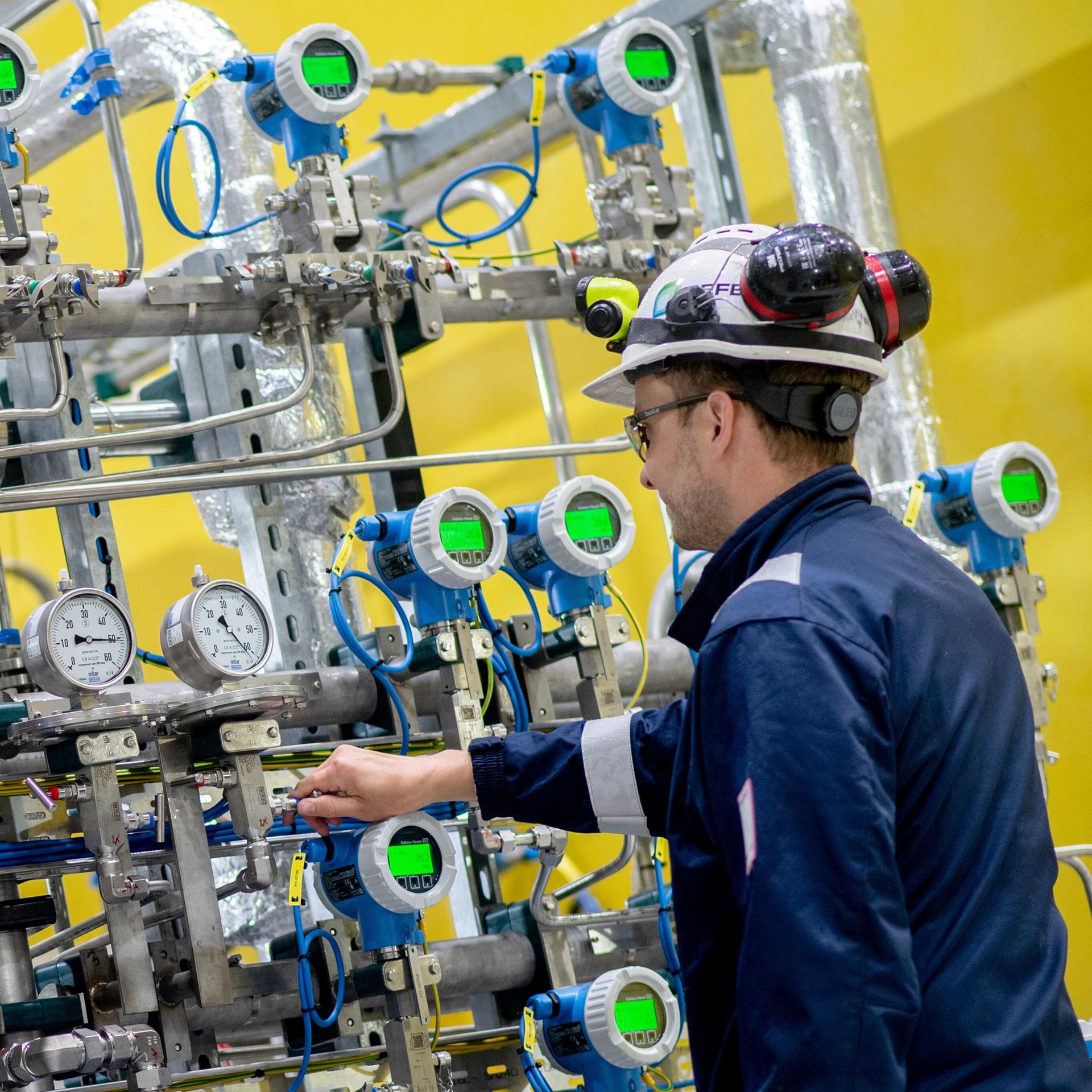 Ein Mitarbeiter der SEFE Storage GmbH steht vor der Steuereinheit einer technischen Anlage zur Verdichtung von Erdgas auf dem Gelände des Erdgasspeichers Rehden. 