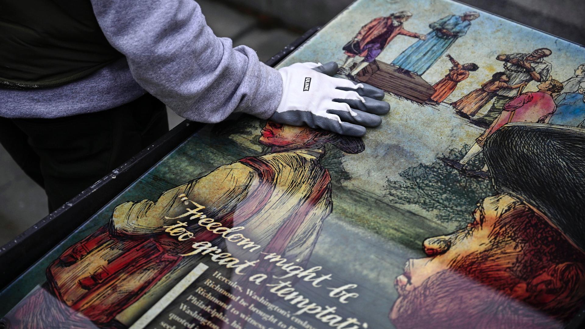 Ein Mitarbeiter des National Park Service legt seine Hand auf eine Tafel, die Teil einer Ausstellung zum Thema Sklaverei am "President’s House Site" in Philadelphia. Ein Mitarbeiter des National Park Service legt seine Hand auf eine Tafel, die Teil einer Ausstellung zum Thema Sklaverei am "President’s House Site" in Philadelphia.