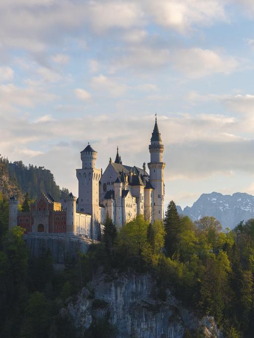Romantisches Schloss vor Alpenkulisse bei Dämmerung, Neuschwanstein, Schwangau bei Füssen, Landkreis Ostallgäu in Bayern
