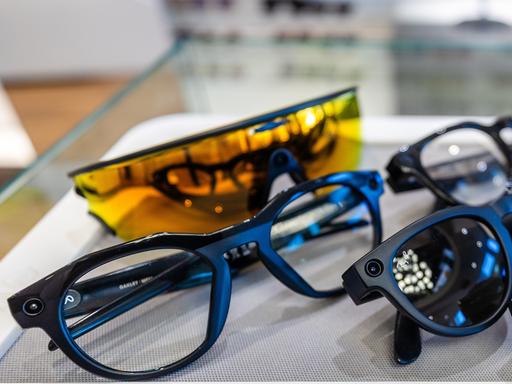 Mehrere Smart Glasses liegen nebeneinander. Einige sind blau eingefasst, eine leuchtend gelb.  