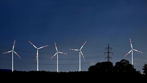 Blick auf einen tiefblauen Himmel mit strahlend weißen Windrädern.