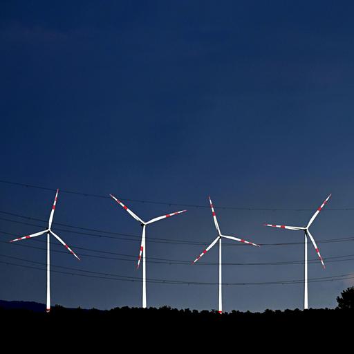 Blick auf einen tiefblauen Himmel mit strahlend weißen Windrädern.