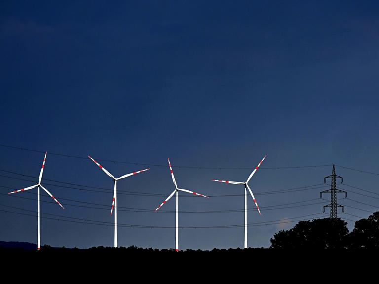Blick auf einen tiefblauen Himmel mit strahlend weißen Windrädern.