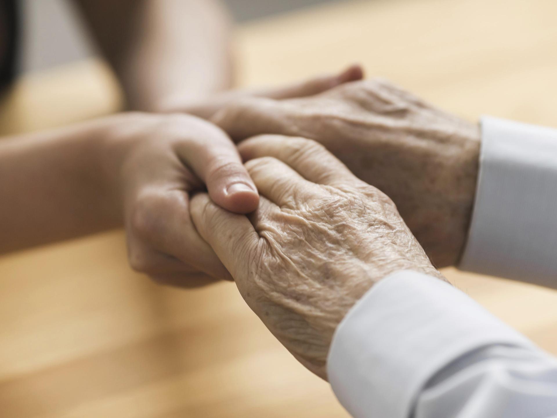 Hände einer jüngeren Frau halten die Hände eines älteren Mannesvorhanden