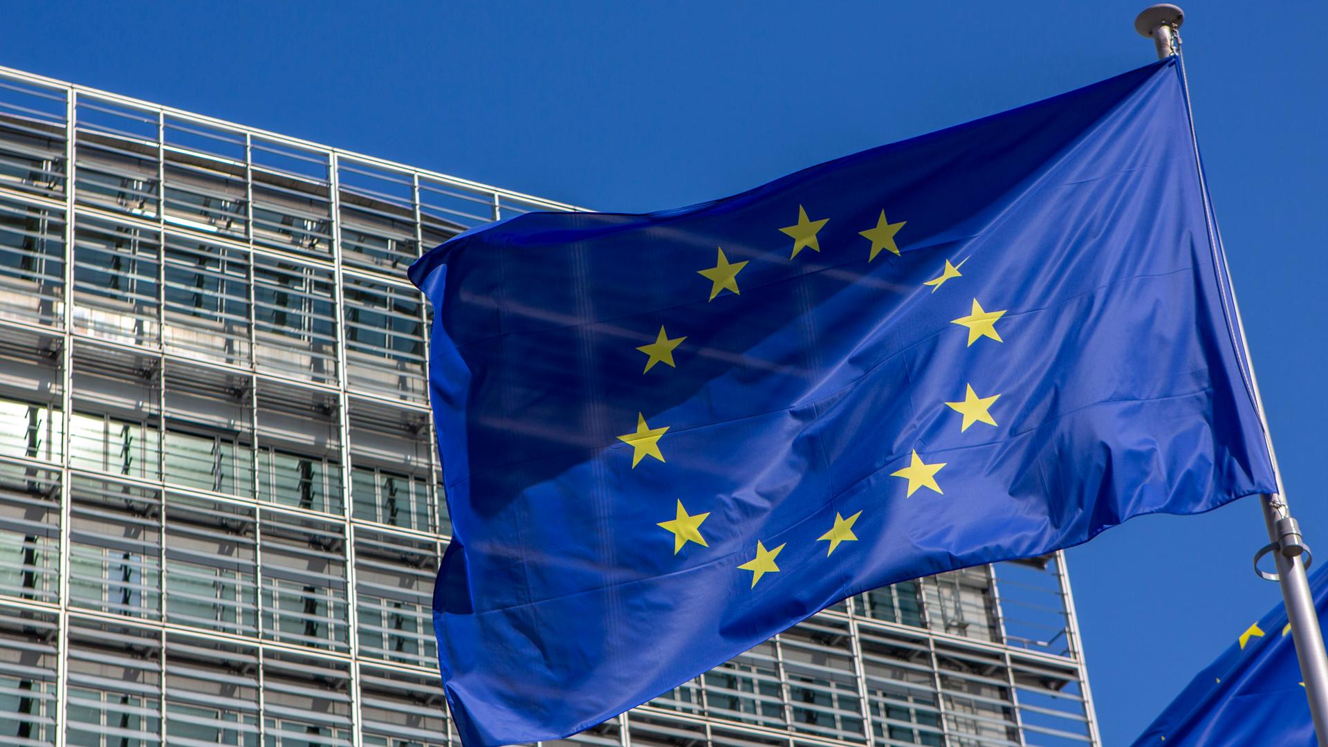 Die blaue EU Flagge mit den gelben Sternen weht vor dem Berlaymont-Gebäude in Brüssel, der Sitz der Europäischen Kommission.