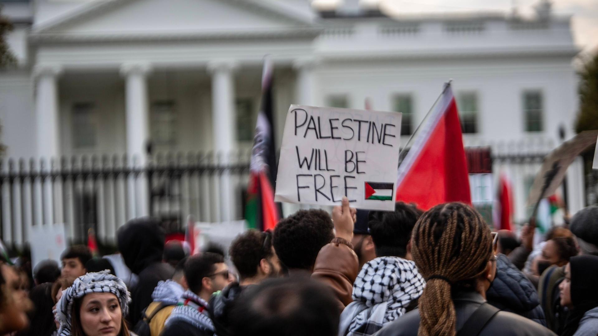 Pro-palästinensische Proteste vor dem Weißen Haus in Washington am 5. November 2023. Das Bild zeigt eine Menschenmenge, die vor einem Zaun steht. Im Hintergrund ist das Weiße Haus leicht verschwommen zu erkennen. Ein Demonstrant hält ein Schild mit der Aufschrift "Palestine will be free" in die Höhe. Pro-palästinensische Proteste vor dem Weißen Haus in Washington am 5. November 2023. Das Bild zeigt eine Menschenmenge, die vor einem Zaun steht. Im Hintergrund ist das Weiße Haus leicht verschwommen zu erkennen. Ein Demonstrant hält ein Schild mit der Aufschrift "Palestine will be free" in die Höhe.