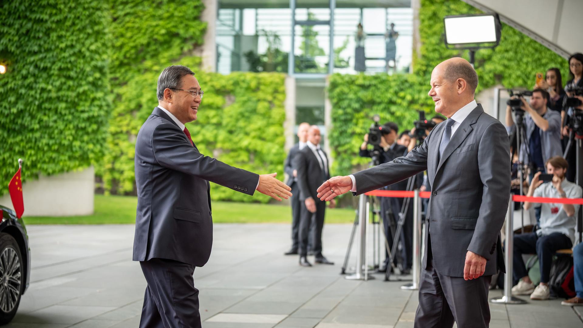 Bundeskanzler Olaf Scholz (SPD, r.) empfängt den chinesischen Ministerpräsidenten Li Qiang mit militärischen Ehren am 20.06.2023 vor dem Bundeskanzleramt. Beide Politiker stehen sich gegenüber und strecken die Hand aus zum Handschlag, bis zur Berührung der Hände fehlen noch rund 20 cm.