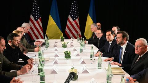 Das Foto zeigt einen langen Tisch. Daran sitzen unter anderem der US-Vizepräsident Vance (rechts, zweiter von vorne) und der ukrainische Präsident Selenskyj (links, zweiter von vorne).