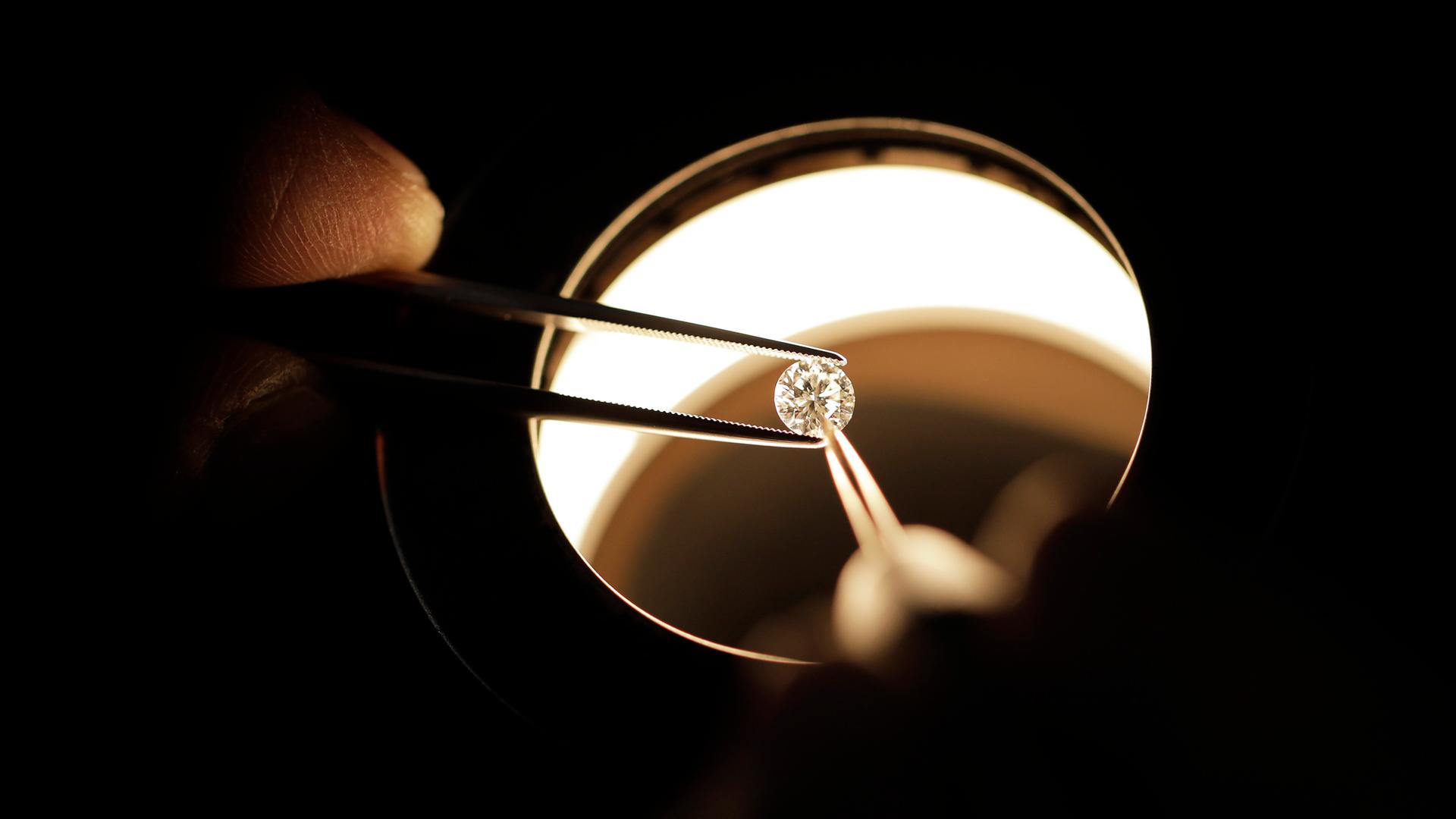 Ein Diamant wird unter einer Lupe begutachtet.