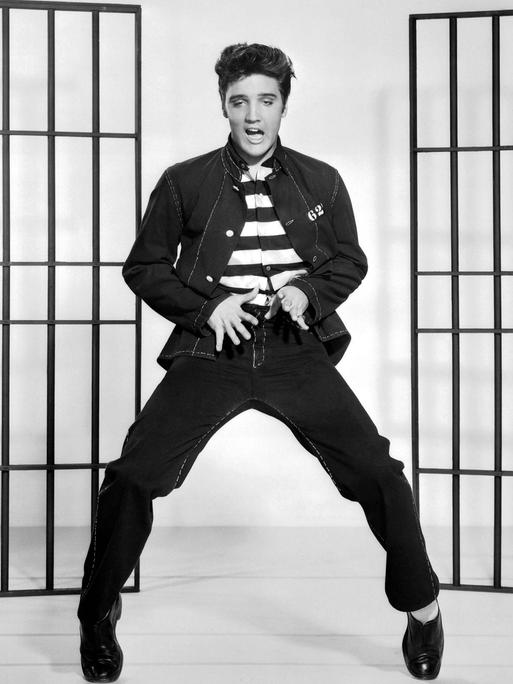 Elvis Presley tanzt und singt im Film "Jailhouse Rock" von 1957 vor einer Gitterdekoration.