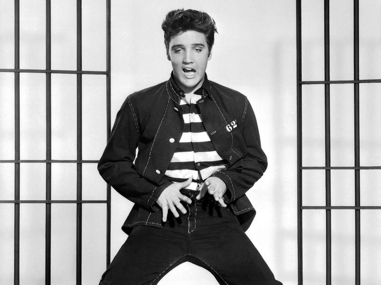 Elvis Presley tanzt und singt im Film "Jailhouse Rock" von 1957 vor einer Gitterdekoration.