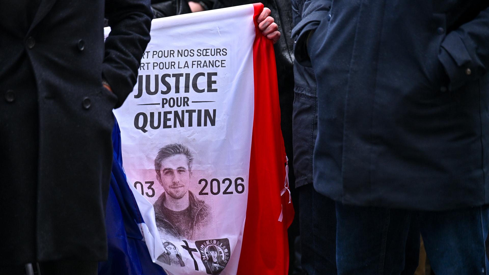 Nahaufnahme auf die Oberkörper mehrerer Menschen, deren Köpfe man nicht sieht. In der Bildmitte ein Transparent mit dem Bild des Opfers und der Schrift "Justice pour Quentin".