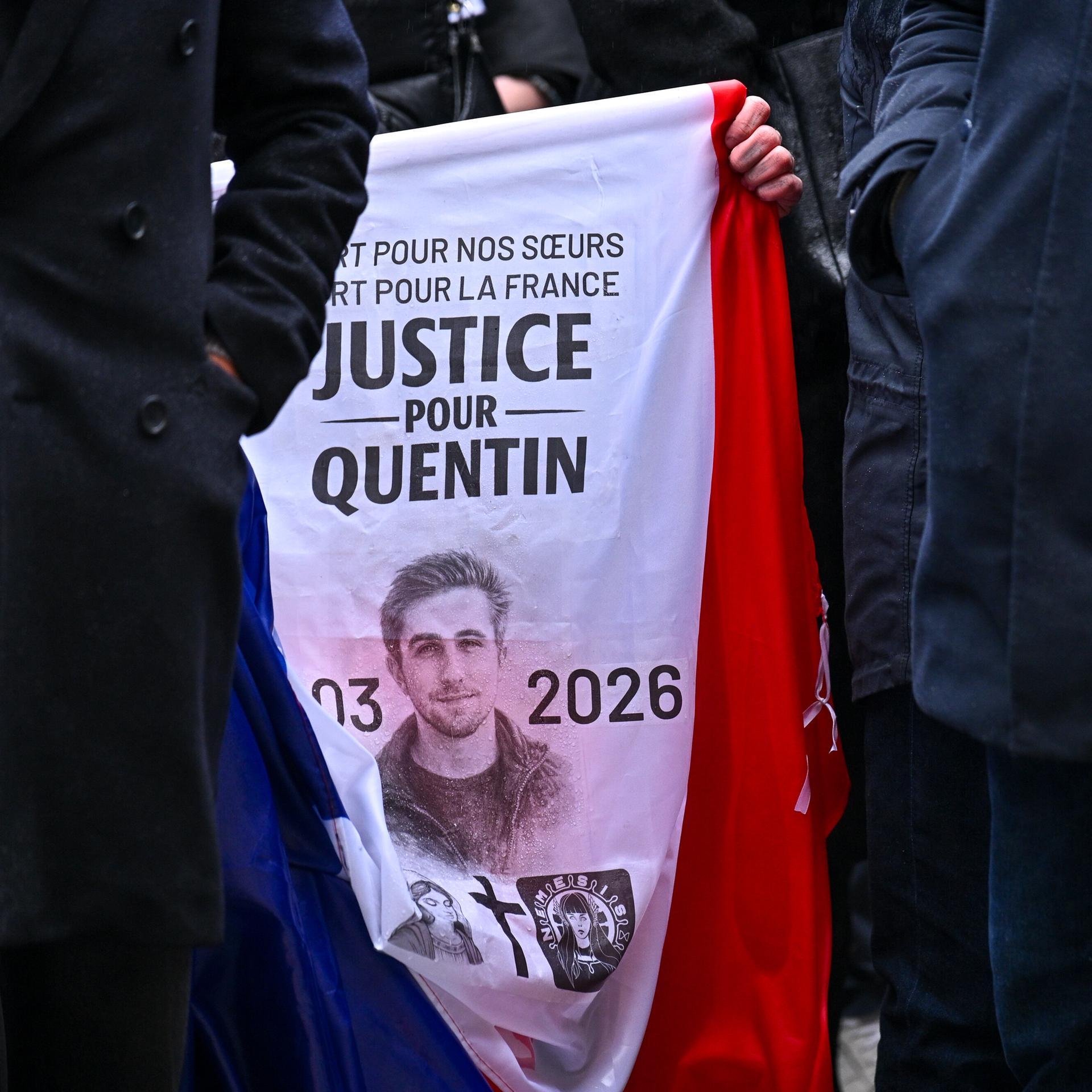 Nahaufnahme auf die Oberkörper mehrerer Menschen, deren Köpfe man nicht sieht. In der Bildmitte ein Transparent mit dem Bild des Opfers und der Schrift "Justice pour Quentin".