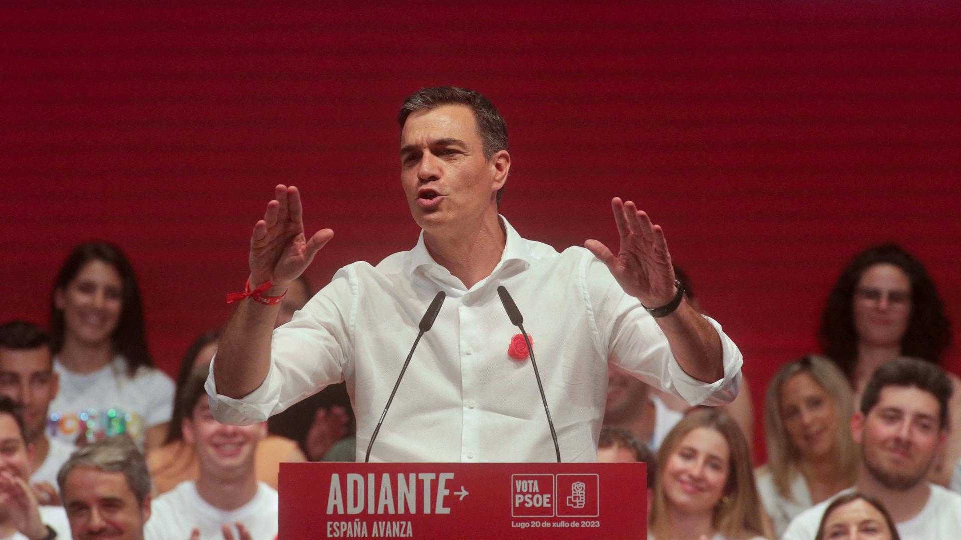 Pedro Sanchez steht bei einer Wahlkampfveranstaltung gestikulierend an einem Pult mit Mikrofonen.