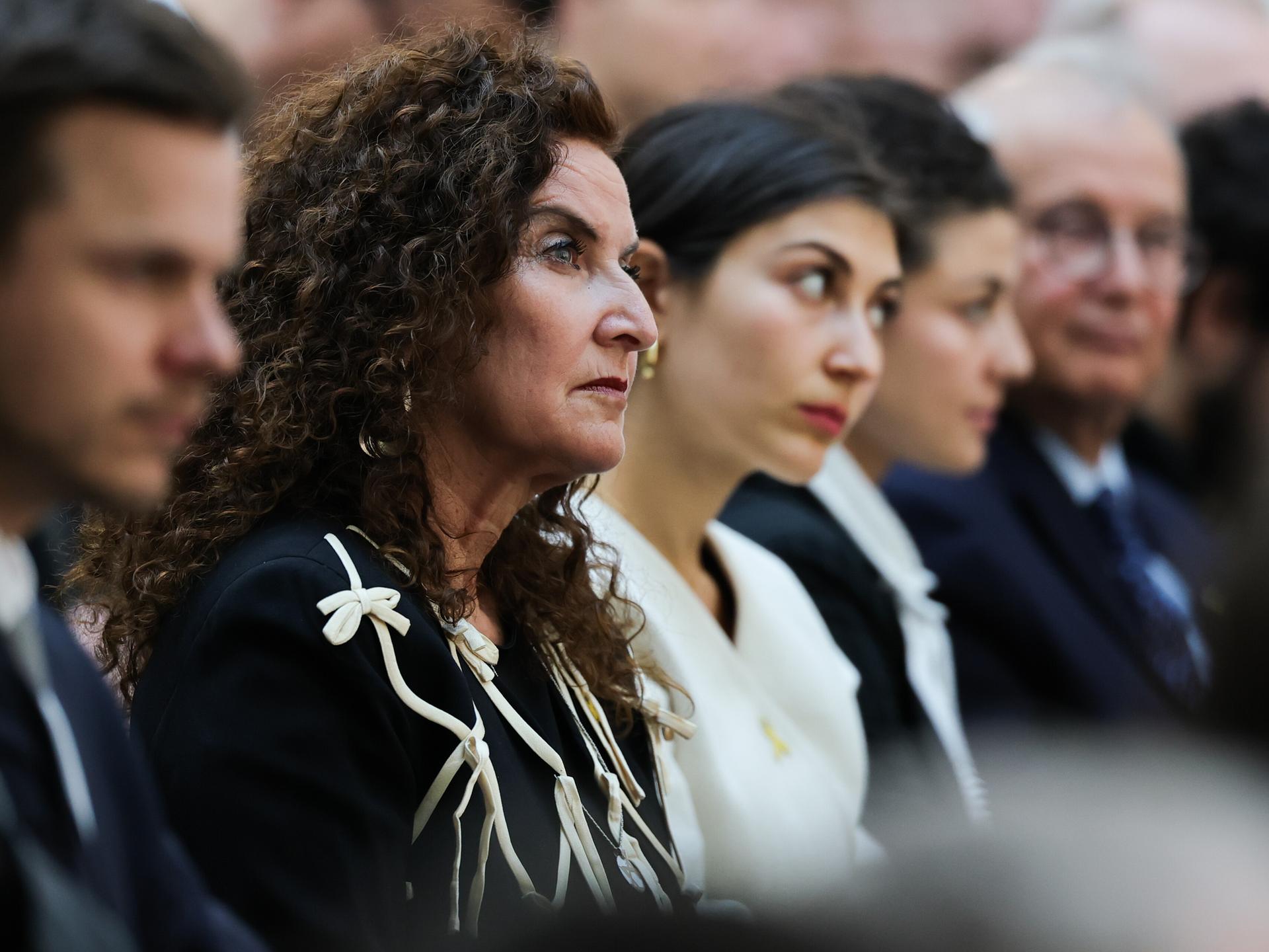 Ilana Lewitan (l), deren Vater Opfer der Shoah geworden ist, und ihre Töchtern Joelle und Lea sitzen bei einer Gedenkstunde für die Opfer des Nationalsozialismus. Sie trägt schwarze Kleidung und schaut nach vorne.