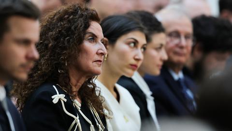 Ilana Lewitan (l), deren Vater Opfer der Shoah geworden ist, und ihre Töchtern Joelle und Lea sitzen bei einer Gedenkstunde für die Opfer des Nationalsozialismus. Sie trägt schwarze Kleidung und schaut nach vorne.