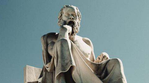 Wir sehen die Statue eines Mannes mit langem Bart, der seinen Kopf auf der Hand abstüzt. 