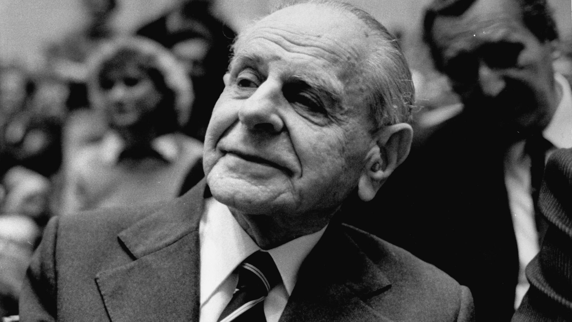 Karl Popper sitzt im Publikum einer Veranstaltung und hört aufmerksam zu