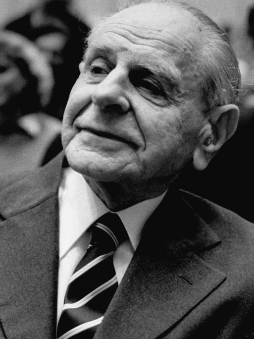 Karl Popper sitzt im Publikum einer Veranstaltung und hört aufmerksam zu