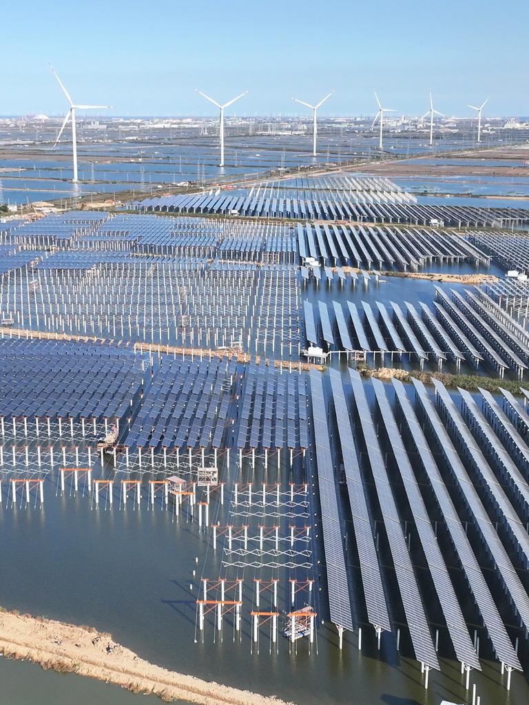 Zu sehen sind großflächige Solarmodule und mehrere Windkraftanlagen. Zu sehen sind großflächige Solarmodule und mehrere Windkraftanlagen.