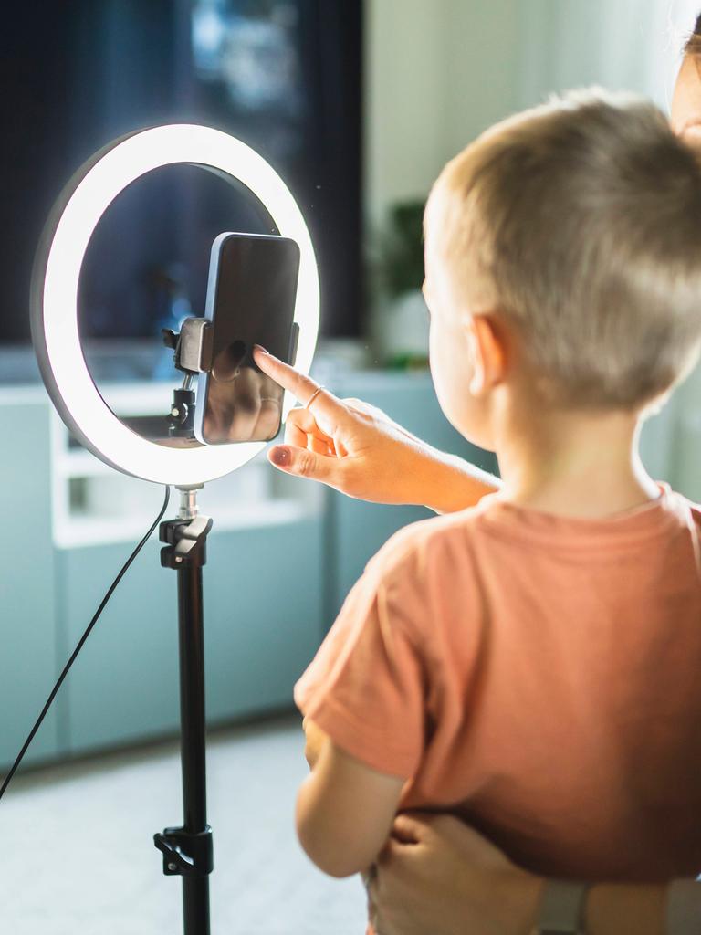 Eine Mutter steht gemeinsam mit ihrem Sohn vor einem Smartphone mit Ringlicht.