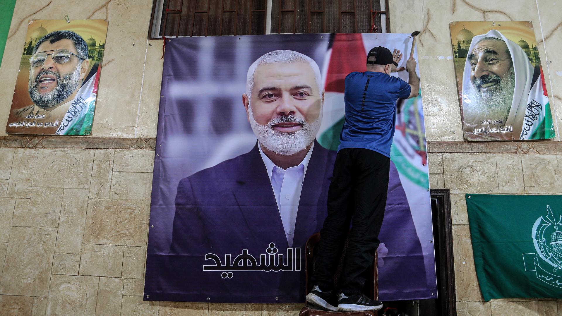 Libanon, Beirut: Ein Mann hängt ein großes Bild von Ismail Hanija in einer Halle auf. Libanon, Beirut: Ein Mann hängt ein großes Bild von Ismail Hanija in einer Halle auf.