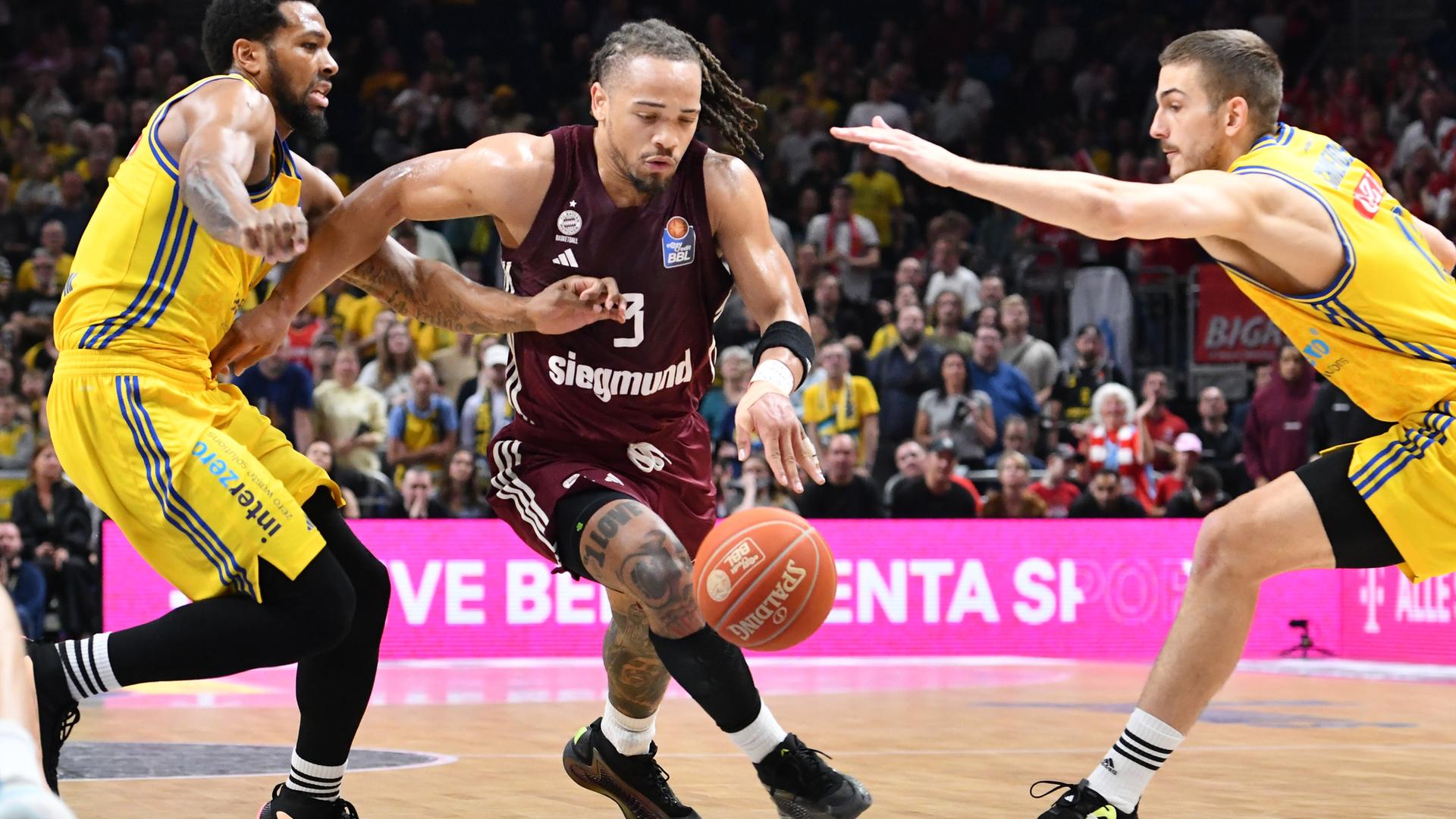 Sterling Brown (links) und Matt Thomas (rechts) von Alba Berlin versuchen Carsen Edwards vom FC Bayern München den Ball abzunehmen. Sterling Brown (links) und Matt Thomas (rechts) von Alba Berlin versuchen Carsen Edwards vom FC Bayern München den Ball abzunehmen.
