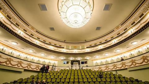 Blick in den festlich erleuchteten Zuschauersaal des Theaters von Mariupol mit grünen Sitzreihen und einem Kronleuchter