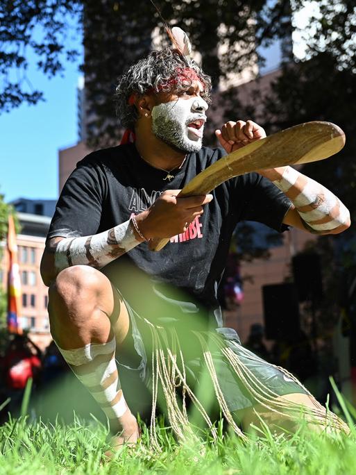 Ein Aborigines-Aktivist tanzt kniend bei einem Protest zum Australia Day.