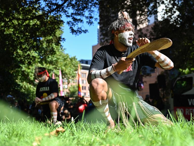 Ein Aborigines-Aktivist tanzt kniend bei einem Protest zum Australia Day.