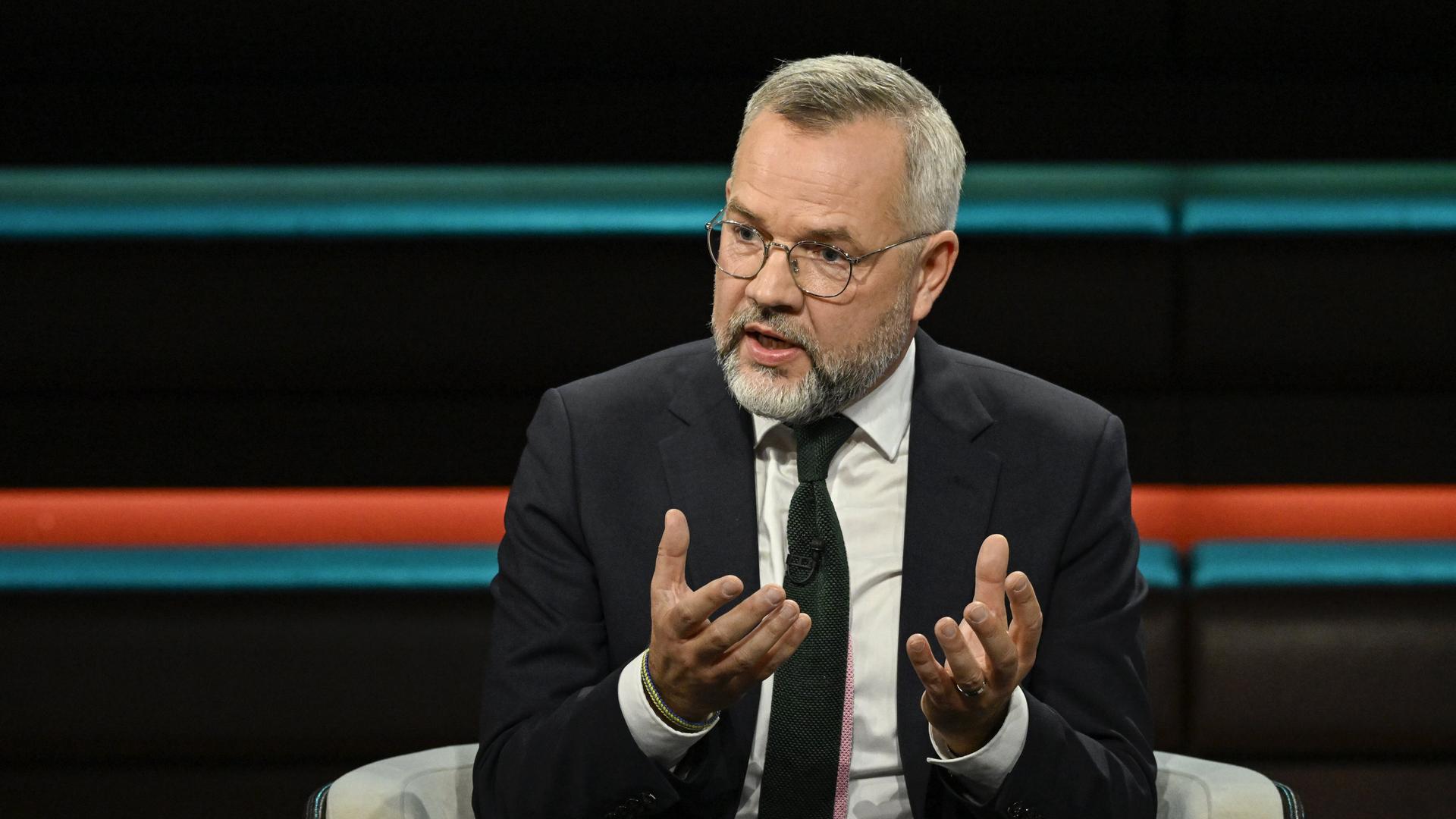 Michael Roth (SPD) sitzt in einem Fernsehstudio und spricht. 