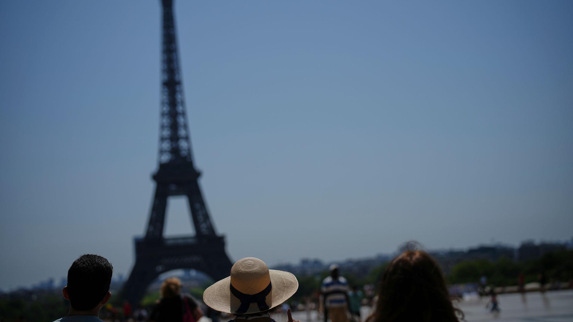 Menschen betrachten den Eiffelturm am Trocadero-Platz während einer Hitzewelle in Paris. Menschen betrachten den Eiffelturm am Trocadero-Platz während einer Hitzewelle in Paris.