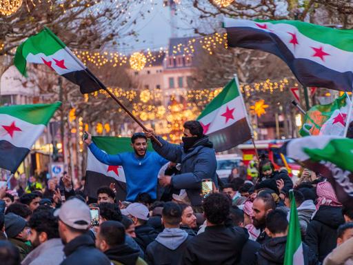 Syrer feiern auf dem Schillerplatz und der Ludwigstraße in Mainz den Sturz des Assad-Regime. Sie schwenken Fahnen und jubeln. 