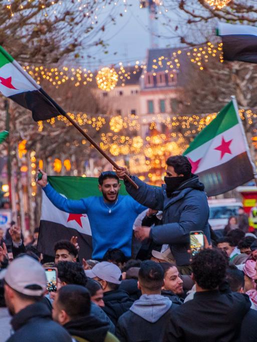 Syrer feiern auf dem Schillerplatz und der Ludwigstraße in Mainz den Sturz des Assad-Regime. Sie schwenken Fahnen und jubeln. 