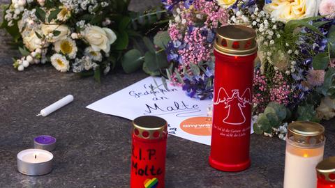 Ein Zettel "Wir gedenken Malte", daneben viele Grablichter und Blumen 