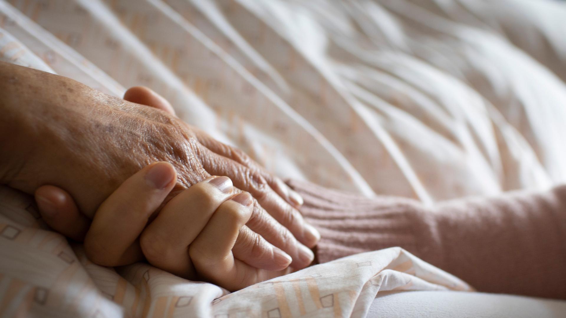 Eine Frau hält die Hand einer Pflegebedürftigen
